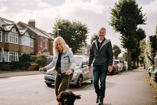 A joyous senior couple walking their dog on a sunny suburban street, enjoying the day.
